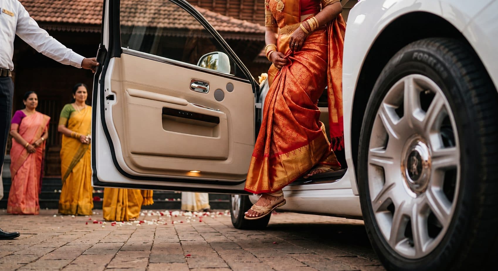 Chauffeur opening the door of a Rolls-Royce wedding car for the bride